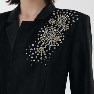 Black blazer with decorative silver embellishments on a plain background