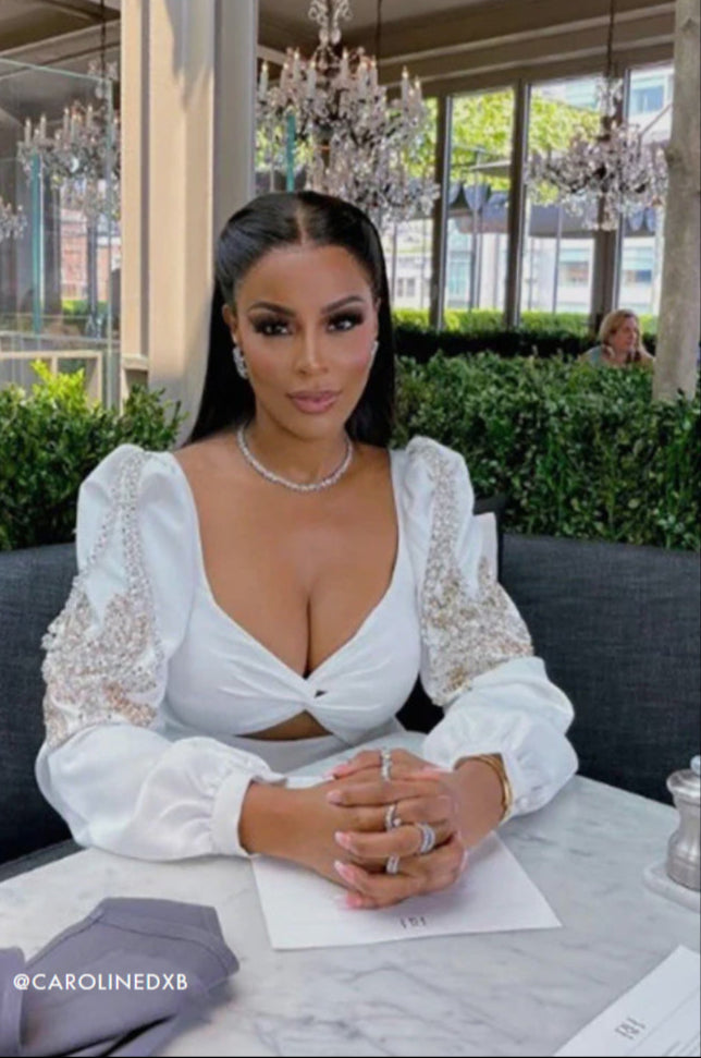 Woman in a white dress sitting at a table in an elegant restaurant.
