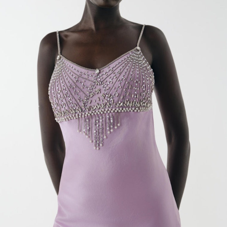 Woman wearing a lavender evening gown with beaded top on a white background