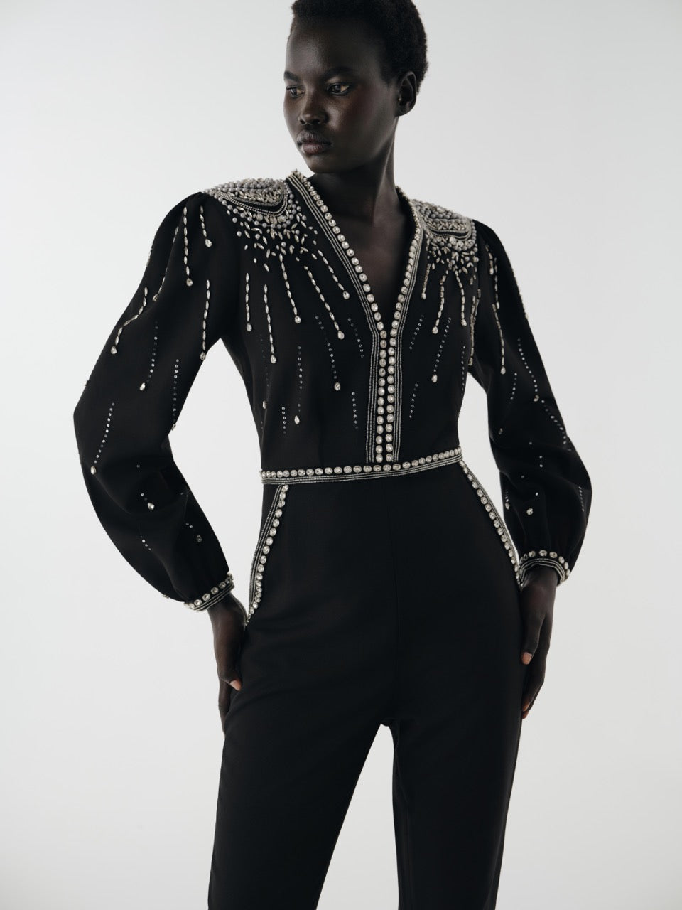 Black jumpsuit with silver embellishments worn by a model on a white background
